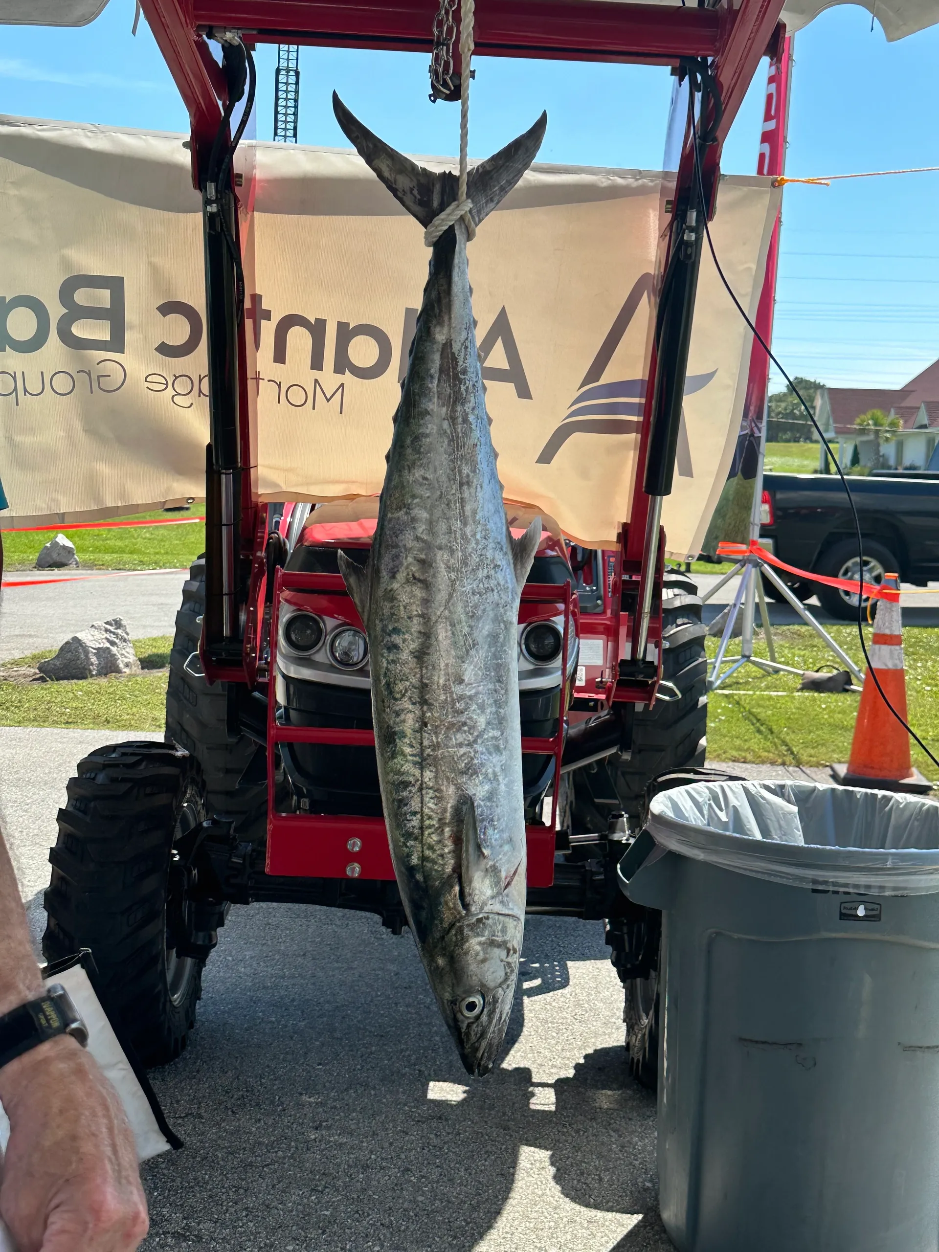 Photo of a large king mackerel on the scales in front of a Mahindra tractor.