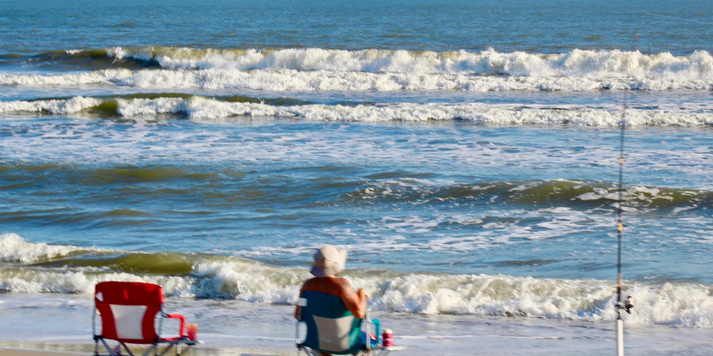 Photo of person fishing from the beach.